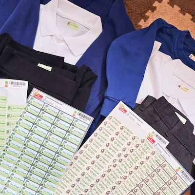 Uniformes escolares azuis e brancos ao lado de folhas de etiquetas termoaderentes