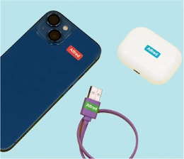 Telemóvel azul e estojo de AirPods com mini autocolantes de nome aplicados