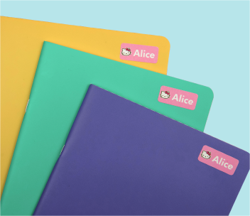 Cadernos amarelo, verde e roxo, cada um com uma etiqueta de nome cor-de-rosa
